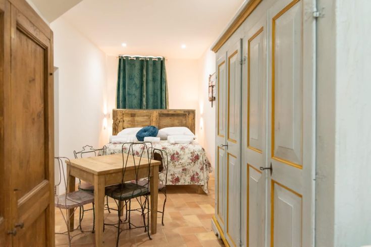 Einfaches Zimmer mit einem Doppelbett, einem Holztisch und einem Schrank.