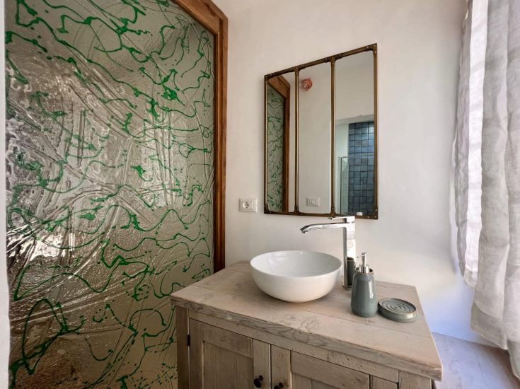 Ein modernes Badezimmer mit einem zeitgenössischen Waschbecken und einer Glaswand. Die Atmosphäre ist angenehm und schlicht.