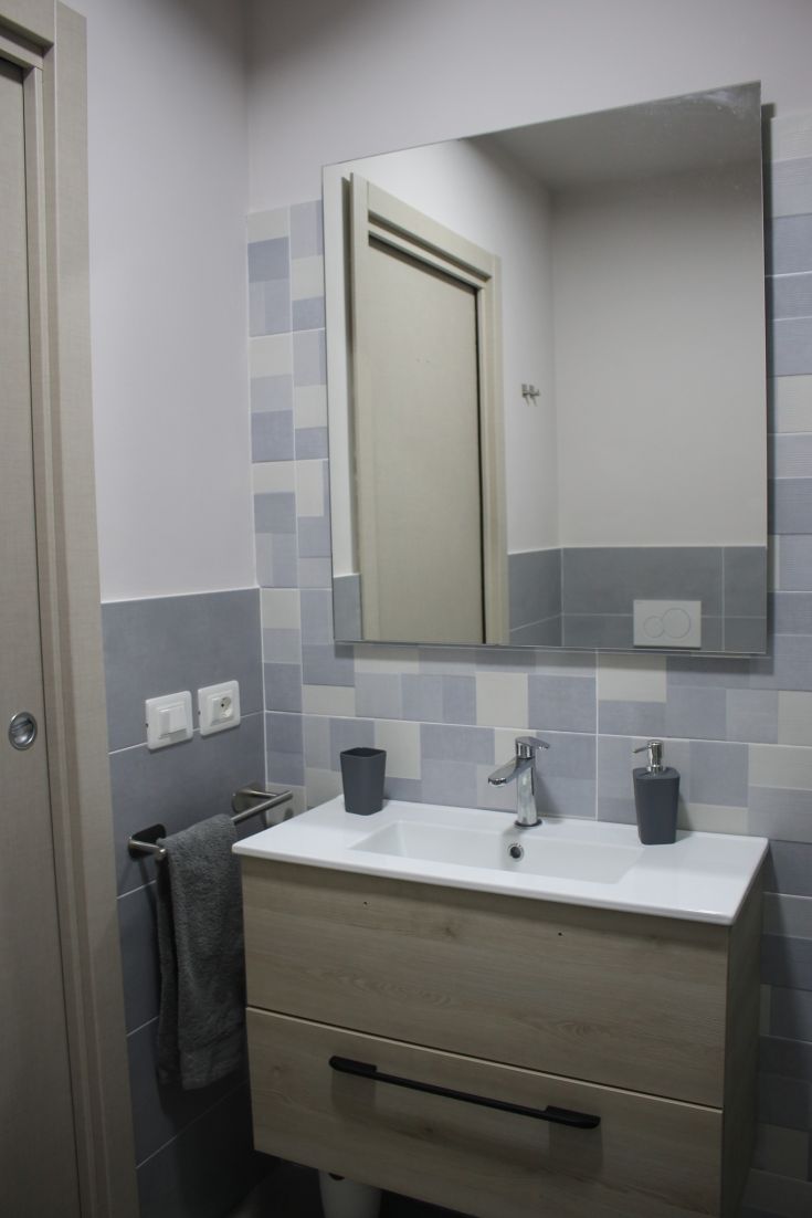 Bagno contemporaneo con lavabo e specchio. Pareti decorate con piastrelle blu e grigio.