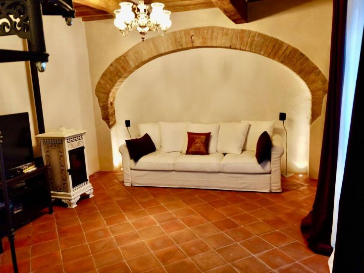 Salotto semplice con divano, stufa e accessori in stile. Spazio adatto per momenti di relax.