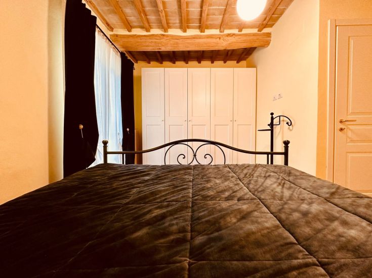 Camera accogliente con letto matrimoniale e armadi, ubicata in un edificio tipico umbro.