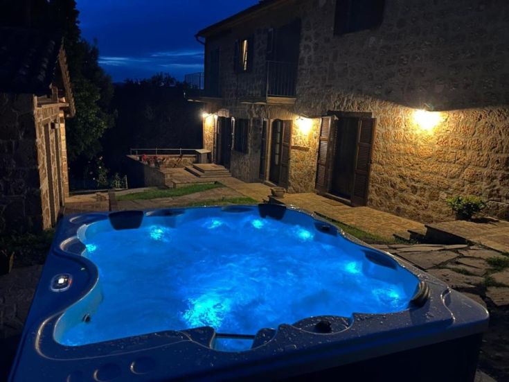 A relaxation corner with a hot tub nestled in the Umbrian countryside, surrounded by lush greenery.
