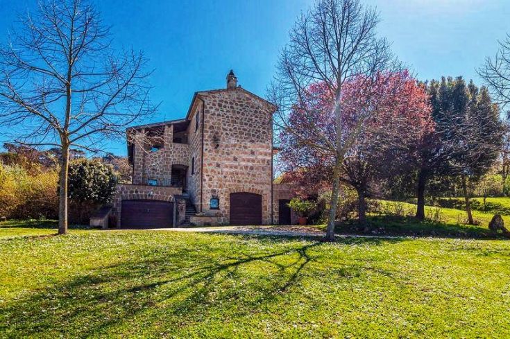 A cozy country building in Umbria, surrounded by olive groves and vineyards in typical regional landscape.