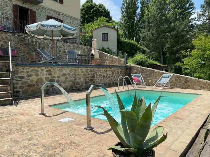 Moments de tranquillité au bord d'une piscine dans un village typique entouré par la nature ombrienne.