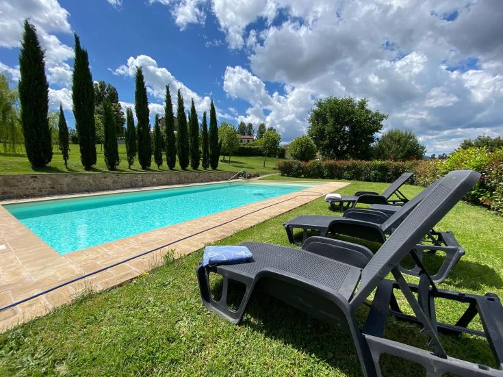 Une piscine nichée dans les collines verdoyantes de l'Ombrie, entourée d'un paysage naturel serein.