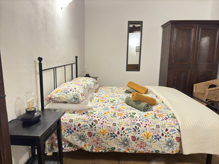 Chambre simple avec un lit décoré et des tissus aux couleurs vives, idéale pour se détendre.