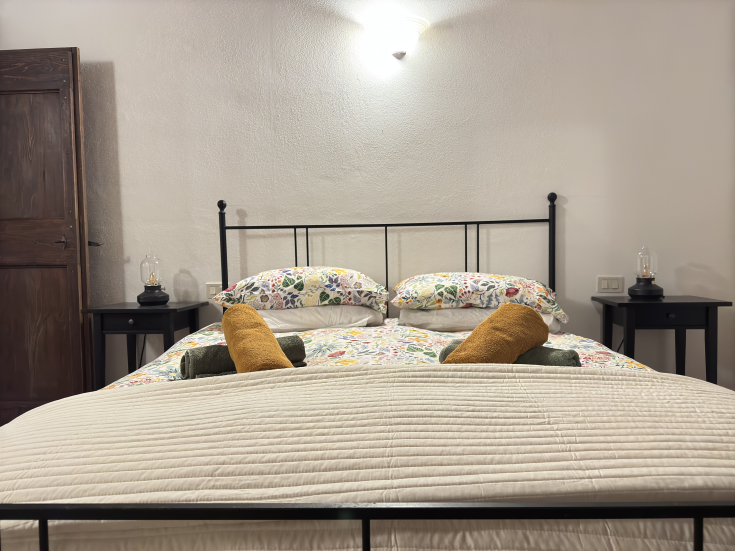 Une chambre simple avec un lit double, des décorations florales, des meubles en bois et un éclairage doux.