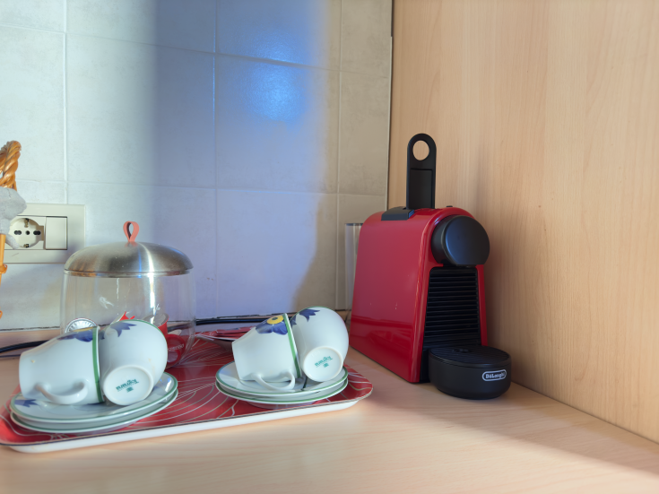 Une cafetière rouge et des tasses blanches sur un plan de travail, idéales pour une pause café.