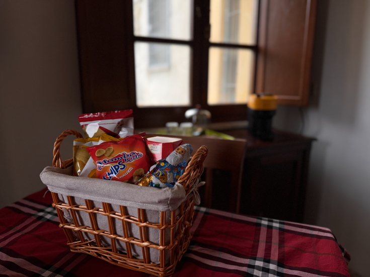 Un panier rempli de différentes collations, posé sur une table décorée d'une nappe à carreaux.