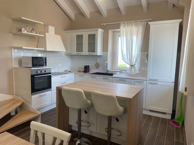 Cucina moderna con isola centrale, luminosa e arredata con semplicità.