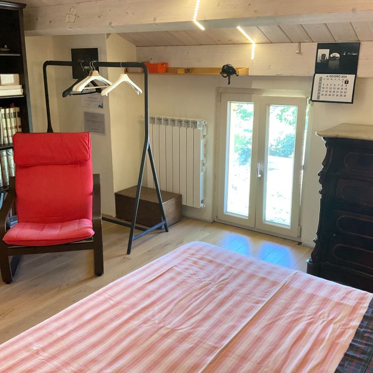 Ein einfaches Zimmerinterieur mit einem roten Sessel und Holzelementen.