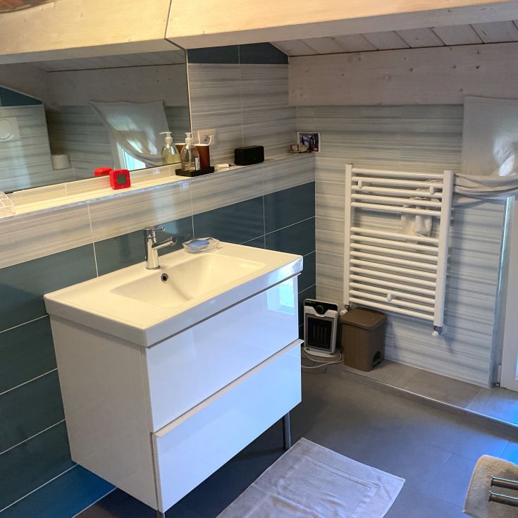 Zeitgemäßes Badezimmer mit Waschbecken und Spiegel, in hellen Tönen und mit schlichten Details eingerichtet.