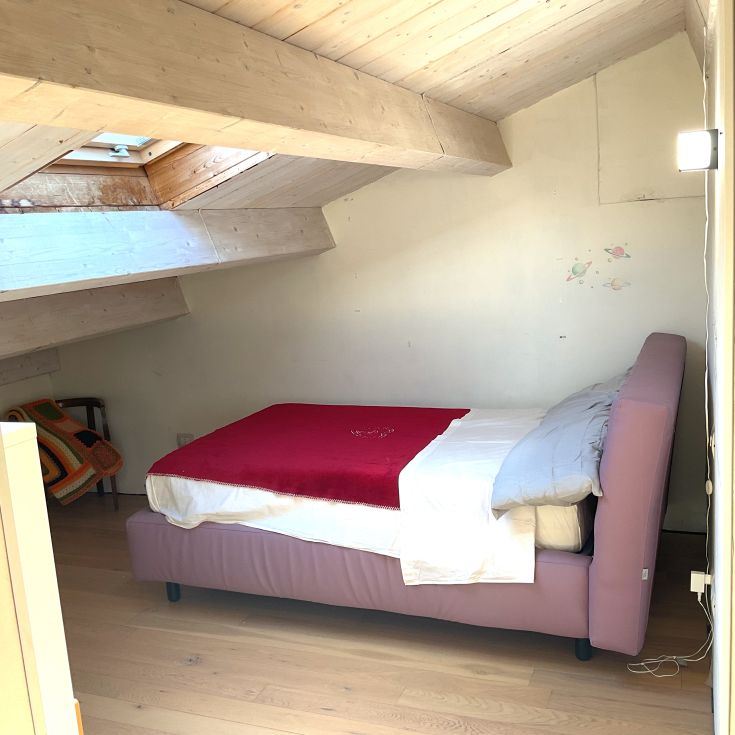 Einfache Schlafzimmer mit einem Doppelbett und einem Holzschrank, perfekt für erholsame Momente.