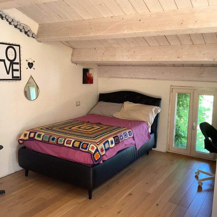 Einfaches Schlafzimmer mit einem Doppelbett und einigen Dekorationen, perfekt zum Entspannen.