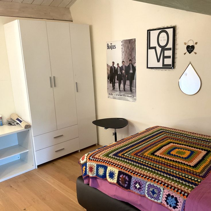 Gemütlicher Raum mit einem verzierten Bett und einem Musikposter. Schlichte und zeitgenössische Einrichtung.