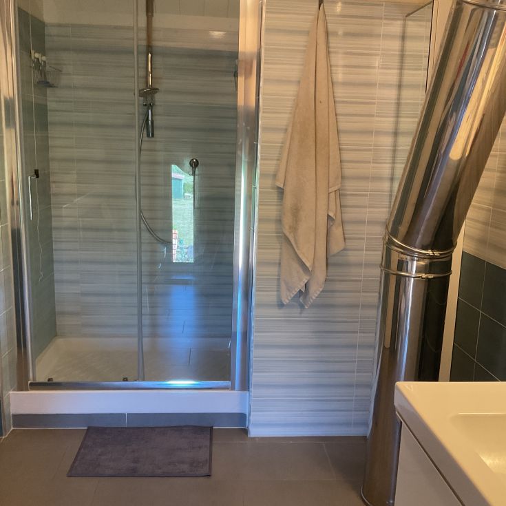 Ein gut eingerichtetes Badezimmer mit Dusche und eleganten Details, beleuchtet von großen Fenstern.