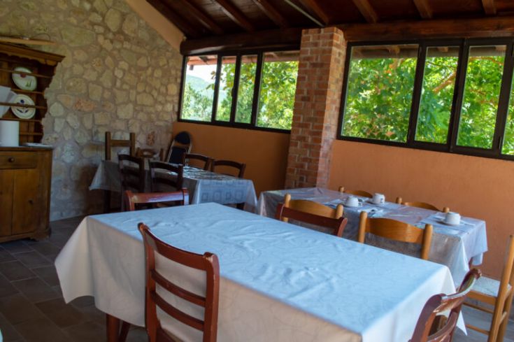Interno del ristorante con tavoli ordinati e panorama su un'area verde circostante.