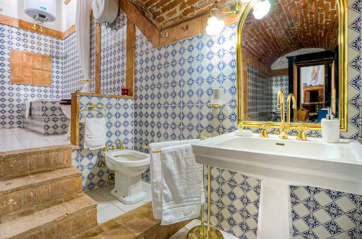 A vintage bathroom with blue tiles and golden touches, creating a cozy, retro atmosphere.