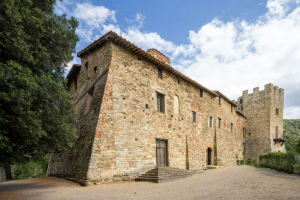 An ancient monastery with a tower, surrounded by green spaces and a clear sky.