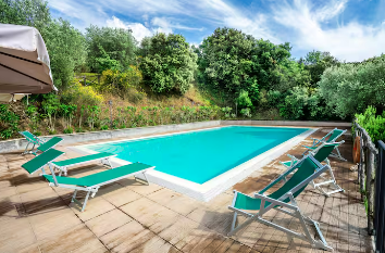 A beautiful view of a pool surrounded by greenery, trees, and lawns, ideal for enjoying peaceful moments.