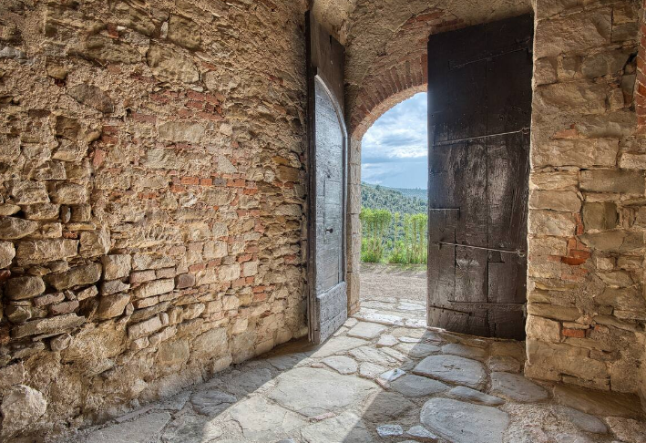 A serene environment with doors opening to a natural landscape, featuring historical elements.