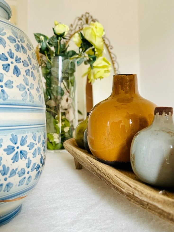 Keramische Vasen und ein Strauß gelber Blumen verleihen dem Raum einen Farbtupfer und Lebendigkeit.