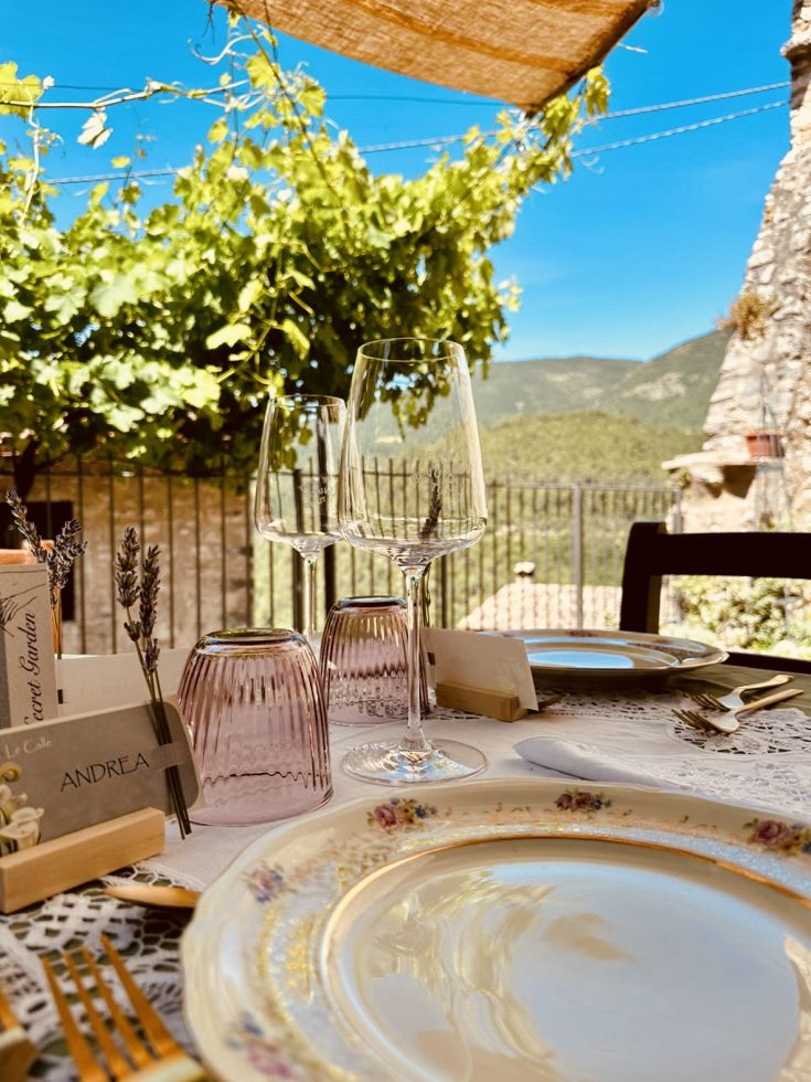 Ein schön gedeckter Tisch im Freien, umgeben von grünen Hügeln, perfekt für ein Mittagessen mit Freunden.