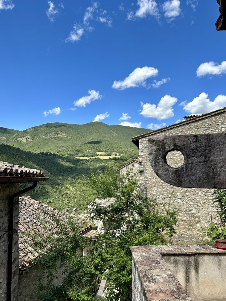 Ruhiges Bergpanorama mit alten Steingebäuden im Vordergrund.