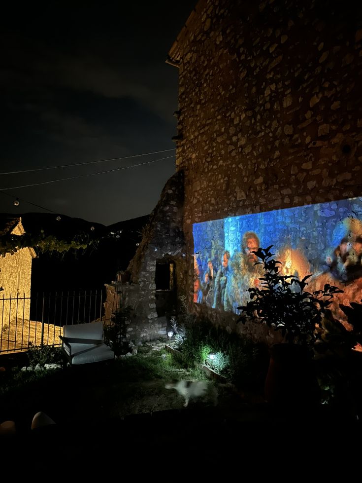 Eine fesselnde Atmosphäre in einem vom Mond beschienen Garten mit einem Film, der auf eine Steinwand projiziert wird.