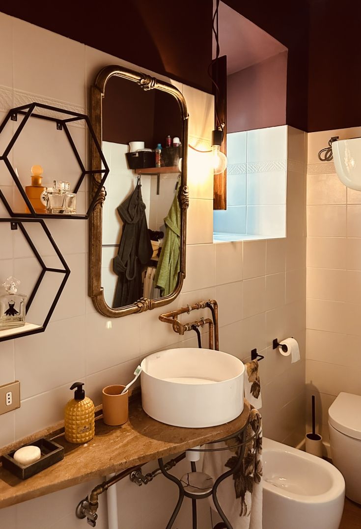 Elegantes Badezimmer mit modernem Design, Vintage-Spiegel und zeitgenössischer Dekoration. Warmes Licht schafft eine gemütliche Atmosphäre.