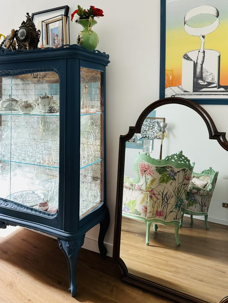 Einfache und gemütliche Interiors mit einem blauen Ausstellungsschrank und einem blumengemusterten Sessel. Eine elegante Ecke.