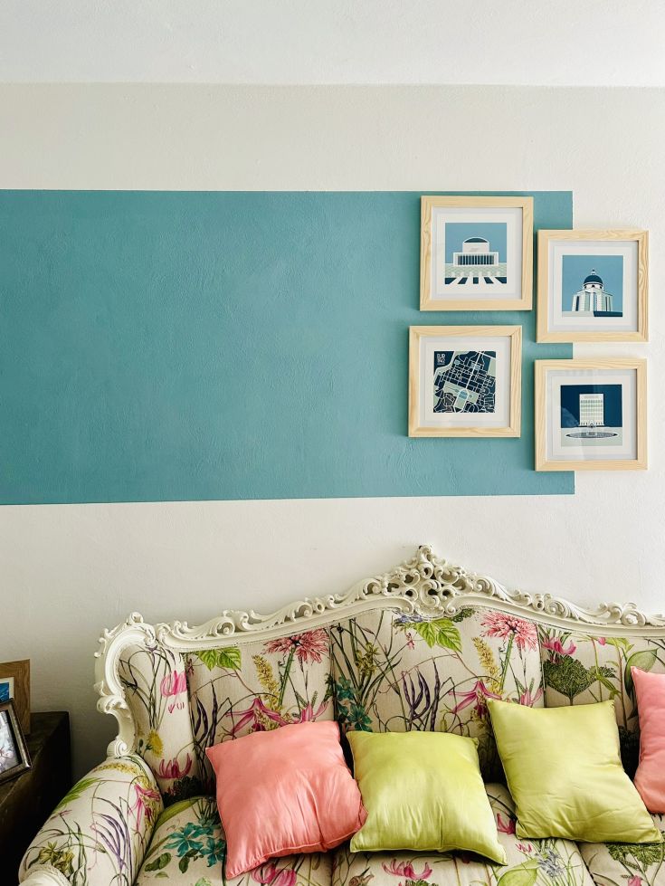 Gemütliche Wohnzimmerszene mit einem blumigen Sofa und Wanddekorationen.