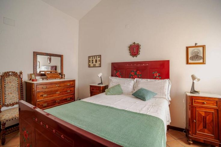 A spacious and comfortable matrimonial bedroom with wooden furniture and floral decorations.