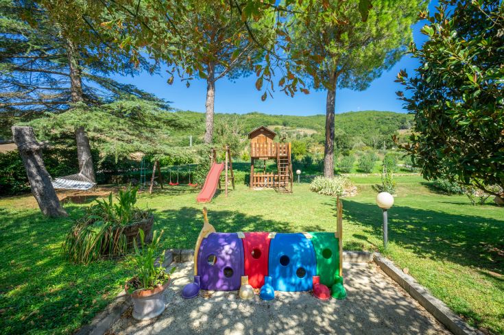 A spacious garden equipped with various play equipment for children, ideal for families.