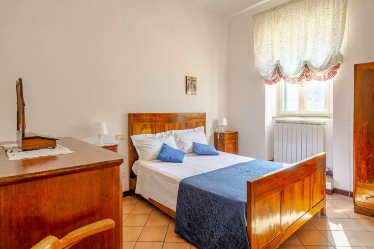 Quiet bedroom with wooden furniture, featuring a bed adorned with a blue bedspread for a cozy feel.