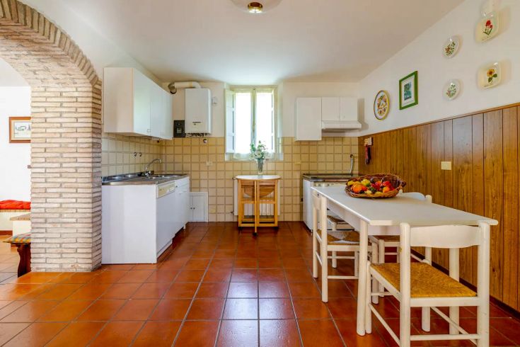 Spacious, well-lit kitchen with wooden elements and tiles, perfect for family meals and gatherings.