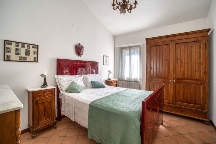 A simple bedroom with wooden furniture and some floral decorations, perfect for relaxation.