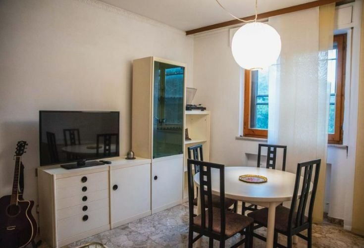 Un soggiorno semplice con TV, un tavolo e una chitarra, adatto a momenti di svago.