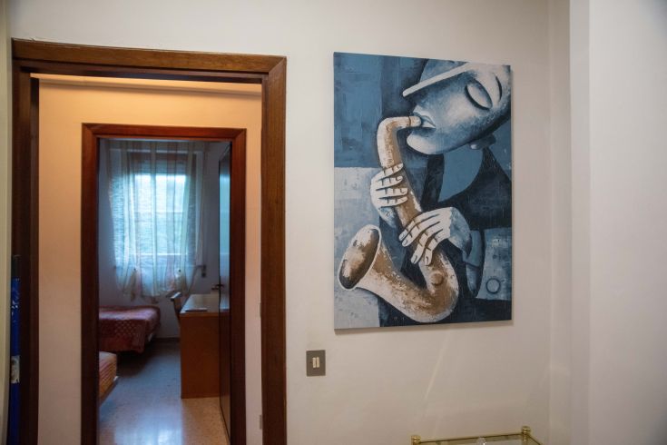 Un musicista suona il saxofono, creando un'atmosfera rilassata nella stanza. Gli arredi sono semplici e contribuiscono a un ambiente accogliente.