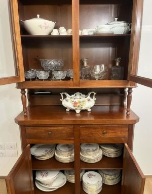 Un mobile in legno con porcellane, bicchieri e piatti esposti.