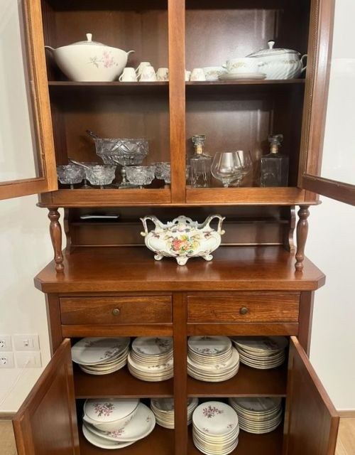 A wooden kitchen cabinet displaying porcelain, glasses, and plates.