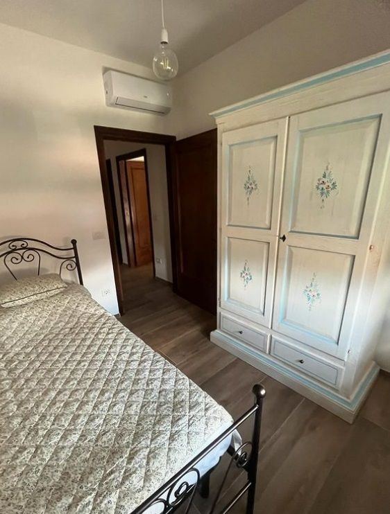 Camera da letto dal design sobrio e confortevole, con armadio in legno e dettagli pratici.