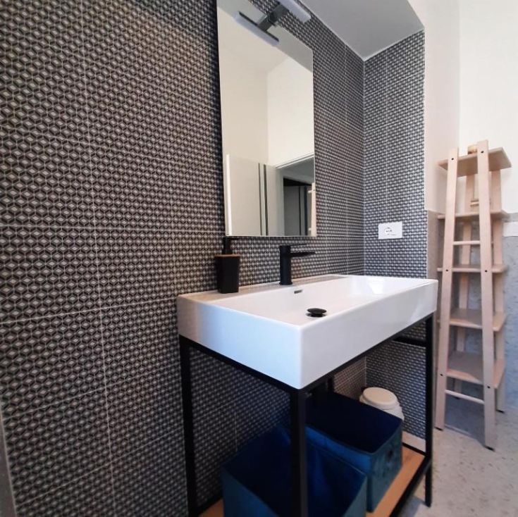 Modernes Badezimmer mit geometrischen Fliesen und einem einfachen Waschbecken.