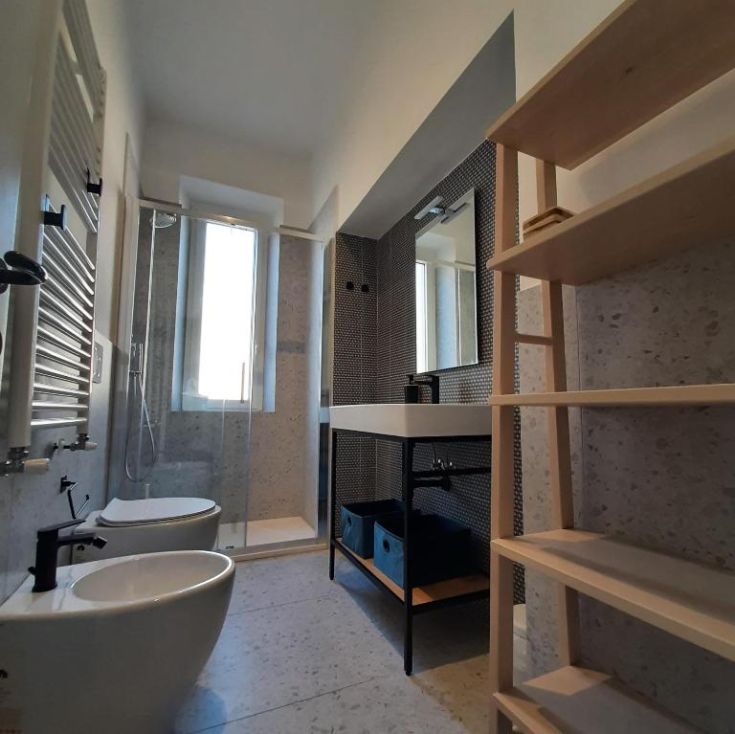 Helles Badezimmer mit Dusche, funktionalen Sanitäranlagen und Platz zum Aufbewahren verschiedener Accessoires.