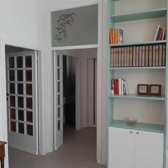 Innenraum einer gut beleuchteten Wohnung, mit einem Bücherregal und Glastüren, die die Räume trennen.