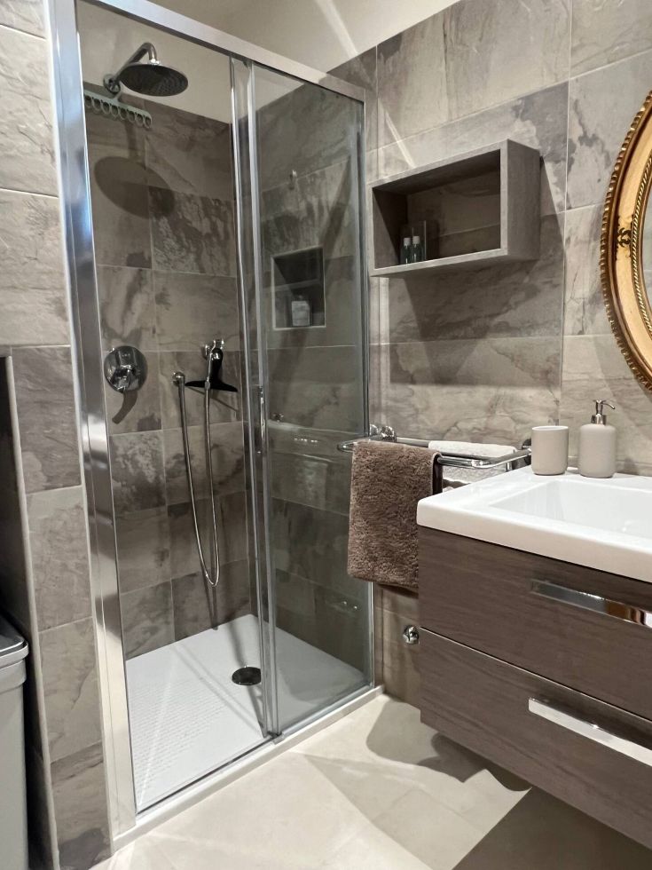 A minimalist bathroom with a glass shower, contemporary furnishings, and stone walls, perfect for everyday use.
