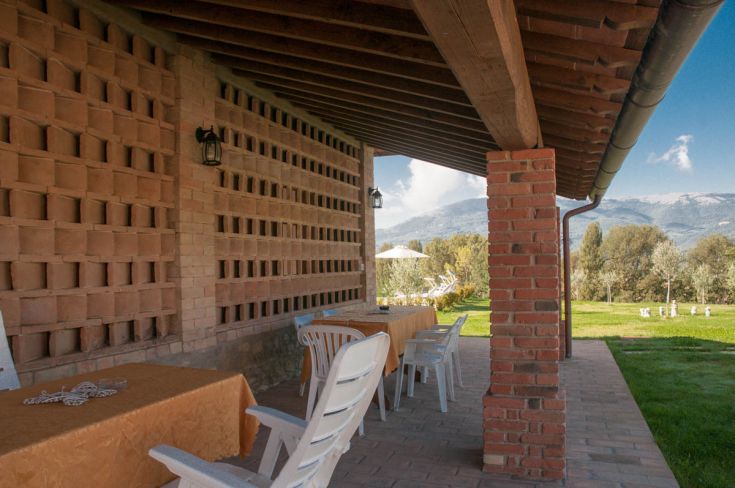 Ampia veranda esterna con tavoli che offre una bella scena sulle colline circostanti.