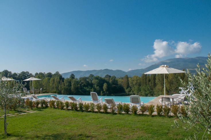 Una piscina immersa nel verde, circondata da alberi. Luogo tranquillo per rilassarsi.