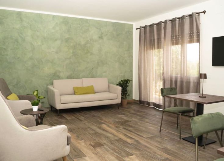 Un salon spacieux et lumineux, caractérisé par des nuances de vert et des meubles au design contemporain, parfait pour la détente.