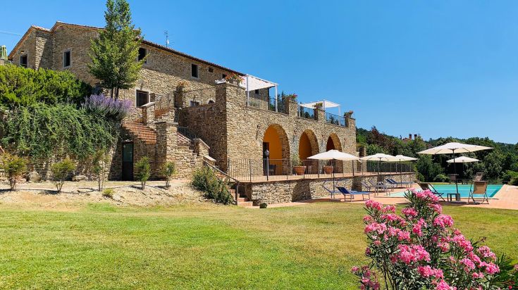 A farmhouse in Umbria with a pool, surrounded by greenery in a peaceful environment.
